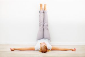 woman lying on her back with her legs up against the wall at 90% angle